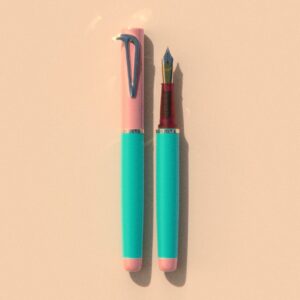 Beaklet Miami writing instrument, capped and uncapped, with a pink cap, aqua barrel and pink end detail.